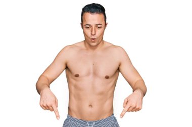 Mayo giyen yakışıklı genç adam parmaklarıyla aşağıya işaret ederek reklamını yapıyor, şaşırmış yüz ve ağzı açık. 