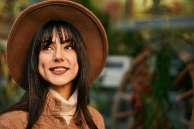 Açık havada gülümseyen, kışlık şapkalı esmer kadın.