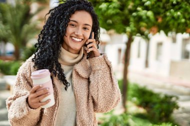 Genç İspanyol kadın gülümsüyor. Parktaki akıllı telefondan konuşuyor.