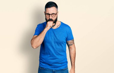 Sakallı, sıradan tişörtlü ve gözlüklü İspanyol bir adam kendini iyi hissetmiyor ve soğuk algınlığı veya bronşitin belirtisi olarak öksürüyor. sağlık hizmeti kavramı. 