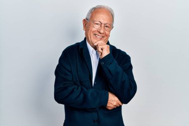 Gri saçlı, sıradan giyinmiş, gözlüklü, kameraya kendinden emin, kolları çapraz ve çenesi havada gülümseyen son sınıf öğrencisi. Olumlu düşünmek. 