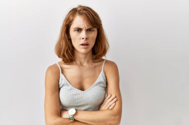 İzole edilmiş arka planda duran beyaz güzel bir kadın şüpheci ve gergin. Yüzünde çapraz kollarla onaylamayan bir ifade var. negatif kişi. 