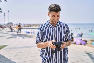 Genç yakışıklı adam deniz kenarındaki DSR fotoğraf makinesini kullanıyor.