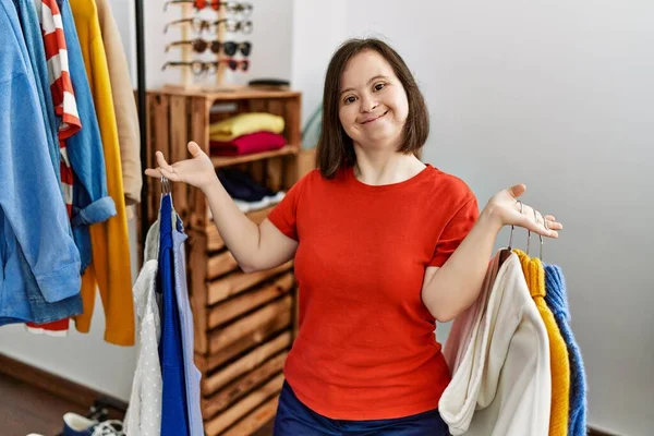 ブルネット女性とともにダウン症候群保持ハンガーで異なる服で小売店 — ストック写真