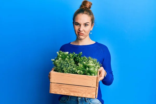 Young Blonde Woman Holding Wooden Plant Pot Skeptic Nervous Frowning — Stock Photo, Image