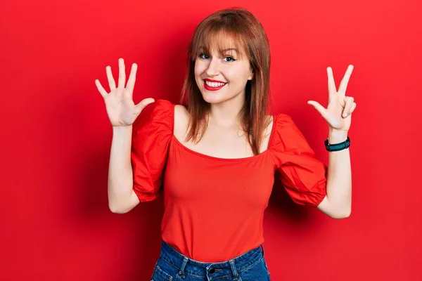Kırmızı Tişörtlü Kızıl Saçlı Genç Bir Kadın Numaralı Parmaklarıyla Gülümseyerek — Stok fotoğraf