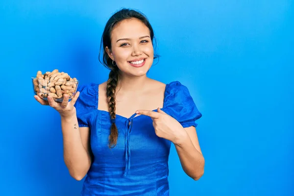 Joven Chica Hispana Sosteniendo Tazón Cacahuetes Sonriendo Feliz Señalando Con — Foto de Stock