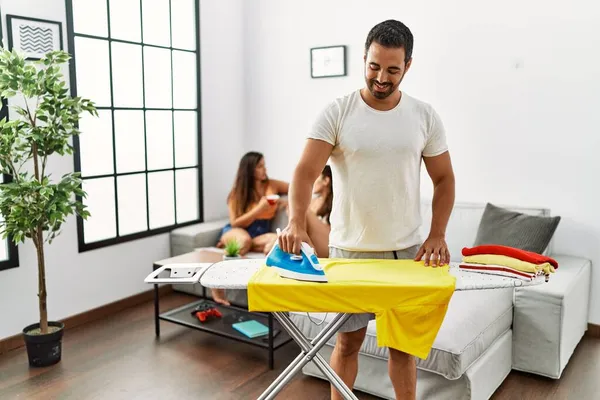 Mann Lächelt Glücklich Beim Bügeln Von Tüchern Wohnzimmer Während Frauen — Stockfoto