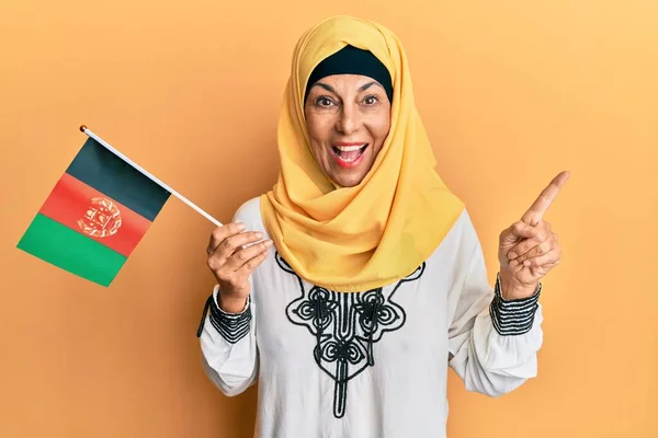Středověká Hispánská Žena Drží Afghánskou Vlajku Šťastně Úsměvem Ukazuje Rukou — Stock fotografie