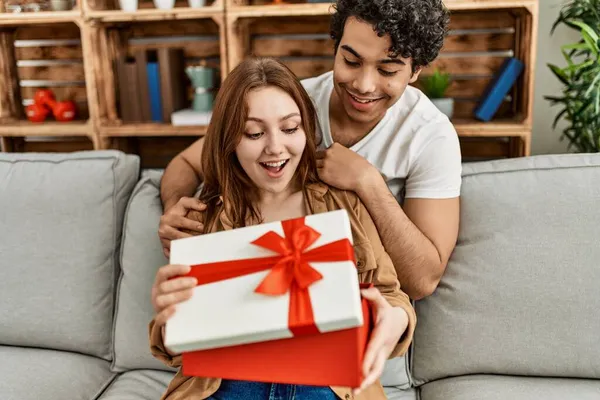 Young Couple Smiling Happy Sitting Sofa Surprise Anniversary Gift Home — Stock Photo, Image
