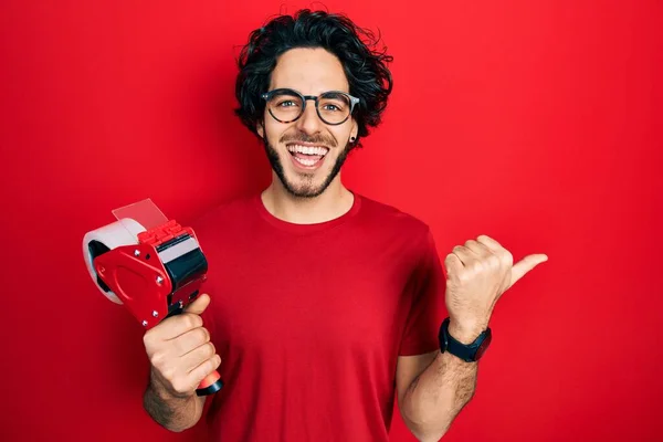 Hezký Hispánec Drží Balicí Pásku Ukazující Palcem Nahoru Stranu Usmívá — Stock fotografie