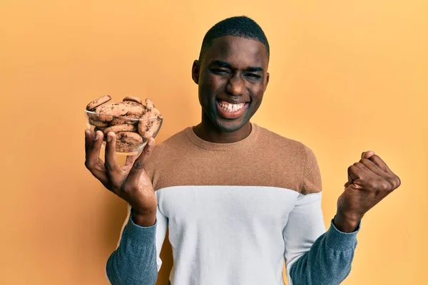 Joven Hombre Afroamericano Sosteniendo Tazón Con Galletas Chispas Chocolate Gritando — Foto de Stock