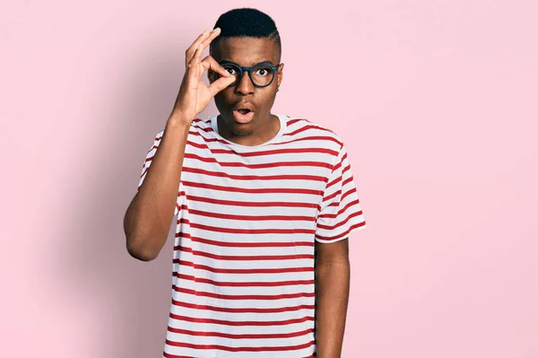 若いアフリカ系アメリカ人の男性は シャツや眼鏡を着用し 驚きの顔でショックを受けたOkジェスチャーを行うと 目を指で見て 信じられない表現 — ストック写真