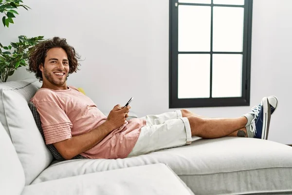 Jovem Hispânico Sorrindo Feliz Usando Smartphone Sentado Sofá Casa — Fotografia de Stock