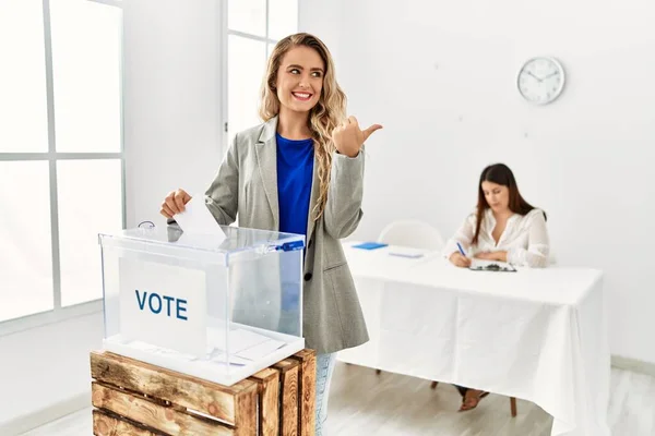 Mujer Rubia Joven Votando Poniendo Sobre Las Urnas Apuntando Pulgar —  Fotos de Stock