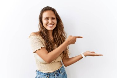 Güzel İspanyol kadın tek başına dikilirken arka plan hayrete düşmüş ve kameraya gülümserken eliyle ve parmağıyla işaret ederek. 