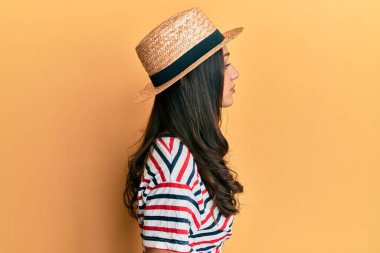 Yazlık şapka takan genç İspanyol kadın, rahat bir görünüm ve kendine güvenen bir gülümsemeyle poz veriyor.. 