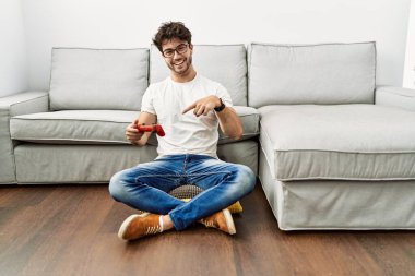 Kanepenin yanında video oyunu oynayan İspanyol adam mutlu bir şekilde elini ve parmağını gösterdi. 