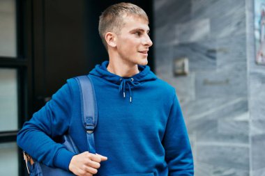 Üniversitede mutlu bir şekilde gülümseyen genç sarışın öğrenci..