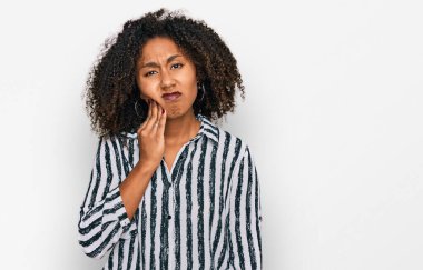 Sıradan kıyafetler giyen, diş ağrısı ya da diş hastalığından dolayı acı dolu bir ifadeyle dudaklarına dokunan Afro-Amerikalı genç bir kız. dişçi 