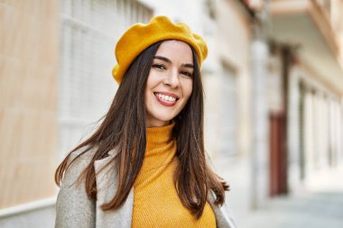 Genç İspanyol kız gülümseyerek şehirde mutlu mesut dikiliyor..