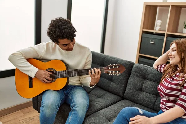 Jovem Casal Sorrindo Feliz Tocando Guitarra Clássica Sentado Sofá Casa — Fotografia de Stock