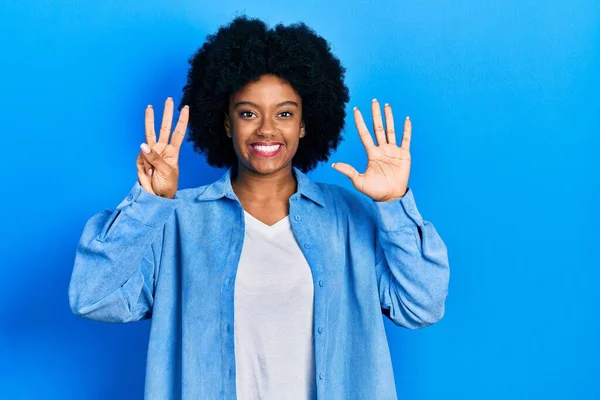 自信を持って幸せな笑顔ながら 若いアフリカ系アメリカ人の女性は カジュアルな服を着て指の数8で示すと指摘します — ストック写真
