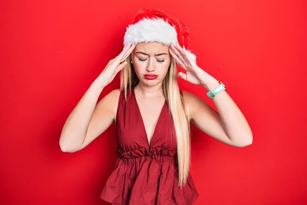 ストレスのために頭の中で痛みのために頭の上に手でクリスマスの帽子をかぶって若いブロンドの女の子 片頭痛 — ストック写真