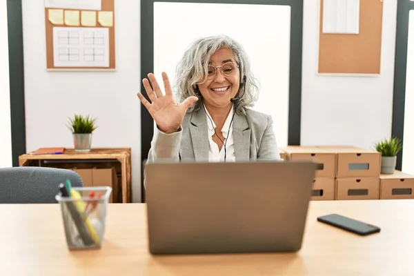 中年女商人坐在办公桌前 用笔记本电脑在办公室里展示 用手指指了指5号 面带微笑 自信而快乐 — 图库照片