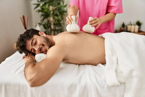 Joven Hombre Hispano Sonriendo Feliz Recitando Bolsas Hierbas Masaje Tailandés —  Fotos de Stock