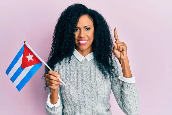 中年アフリカ系アメリカ人女性のアイデアや質問を笑顔でキューバフラグを保持幸せな顔を指を指して ナンバーワン — ストック写真