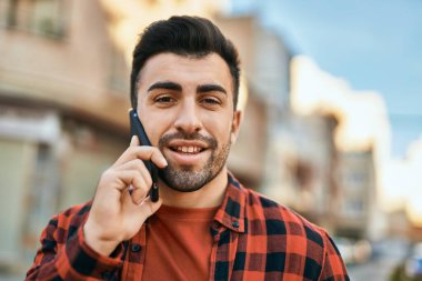 Genç İspanyol adam gülümsüyor. Şehirdeki akıllı telefondan konuşuyor..