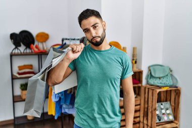 Perakende dükkanında sakallı, alışveriş torbası tutan genç yakışıklı adam uykulu ve yorgun görünüyor, yorgunluktan yorgun ve akşamdan kalma, sabahları tembel gözler.. 