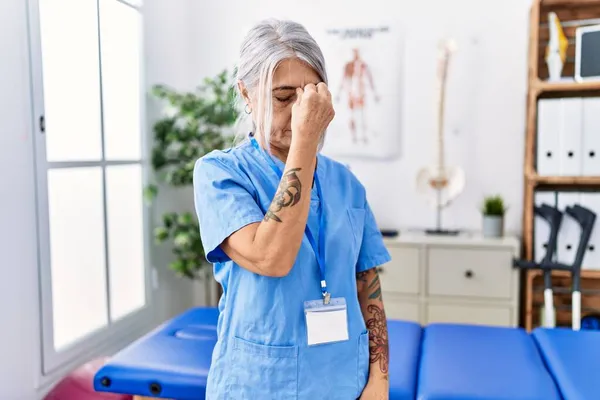 Medelålders Gråhårig Kvinna Bär Sjukgymnast Uniform Läkarmottagningen Trött Gnugga Näsa — Stockfoto