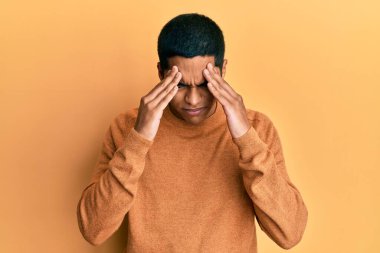 Genç, yakışıklı İspanyol bir adam, stresten dolayı elleri başının üstünde, günlük bir kazak giyiyor. migren ağrısı. 