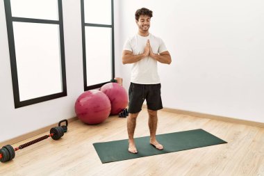 Genç İspanyol adam gülümsüyor spor merkezinde yoga antrenmanı yapıyor.