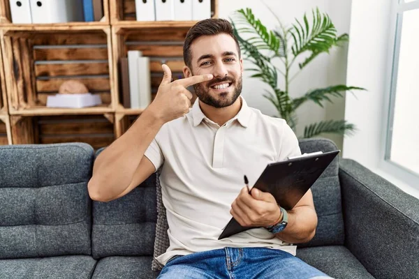 Hombre Hispano Guapo Sosteniendo Portapapeles Trabajando Clínica Psicología Señalando Con — Foto de Stock