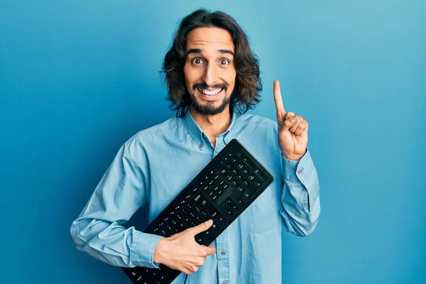 Νεαρός Ισπανός Κρατώντας Πληκτρολόγιο Χαμογελώντας Μια Ιδέα Ερώτηση Δείχνοντας Δάχτυλο — Φωτογραφία Αρχείου