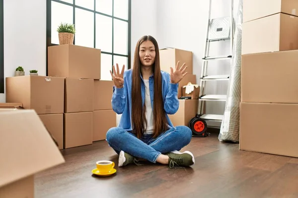 Joven Chica China Sentada Suelo Nueva Casa Mostrando Señalando Hacia — Foto de Stock