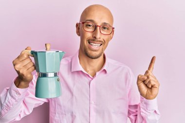 Kel, sakallı, İtalyan kahvesi içen, gülümseyen, eli ve parmağı kenarda mutlu bir adam. 