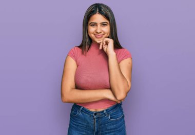 Gündelik tişört giyen genç İspanyol kız kameraya kollarını kavuşturup gülümseyerek ve çenesini kaldırarak bakıyor. Olumlu düşünmek. 