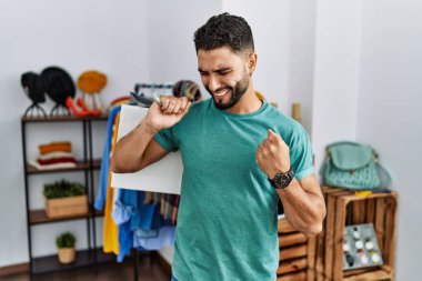 Satış mağazasında sakallı yakışıklı bir adam çok mutlu ve heyecanlı bir şekilde kolları havada, gülümseyen ve başarı çığlıkları atan bir jest yapıyor. kutlama konsepti. 