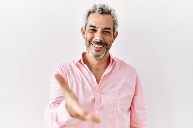 Orta yaşlı İspanyol bir adam izole edilmiş arka planda durup dostça el sıkışarak selamlama ve hoş geldin diyor. başarılı iş. 