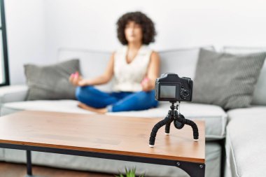 Orta Doğulu genç bir kadın evde yoga dersi veriyor.