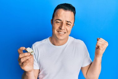 Yakışıklı genç adam çiğ istiridye tutuyor gururla bağırıyor, zaferi ve başarıyı kutluyor. 