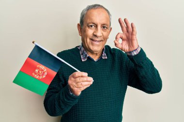 Gri saçlı, Afgan bayrağı tutan yakışıklı yaşlı adam parmaklarıyla imza atıyor, gülümsüyor ve mükemmel bir sembol. 