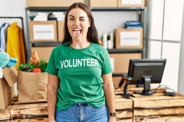 Bağışlarda gönüllü tişört giyen esmer kadın komik bir ifadeyle dilini dışarı çıkartıyor. duygu kavramı. 