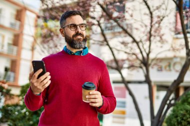 Genç İspanyol yönetici akıllı telefon kullanıyor ve şehirde kahve içiyor..