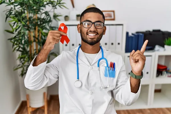 Young Indian Doctor Holding Support Red Ribbon Smiling Happy Pointing — Stock Photo, Image