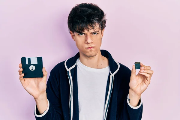 Przystojny Hipsterski Młody Człowiek Trzymający Dyskietkę Kartę Sdxc Sceptyczny Nerwowy — Zdjęcie stockowe